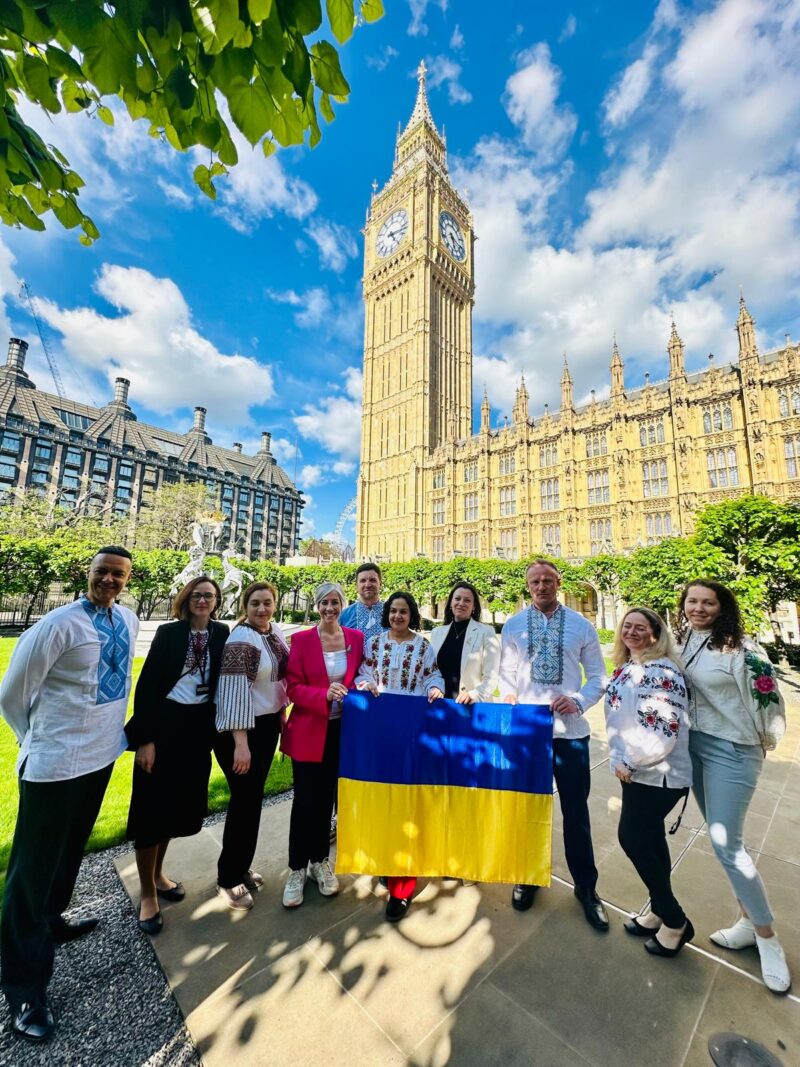 An image of Clive Lewis MP and other MPs and campaigners alongside a Ukrainian flag outside Parliament